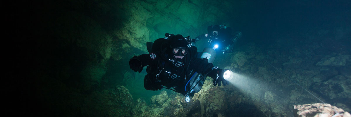 Open Circuit Cave Diving diver swims with a flashlight underwater